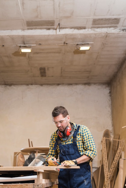 Carpinteiro profissional masculino, tendo a medição na bancada de trabalho na oficina