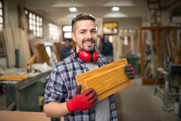 Carpinteiro profissional segurando material de madeira na oficina de carpintaria