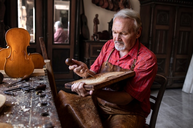 Carpinteiro sênior concentrado, trabalhando pacificamente em sua oficina antiquada em um novo projeto