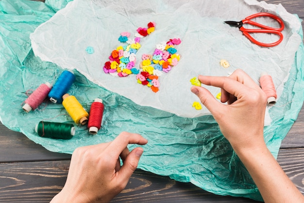 Carretéis de linha colorida; botões em forma de coelho e tesoura sobre papel