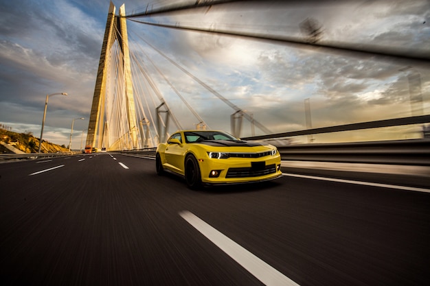 Carro desportivo amarelo com autotuning preto na ponte.