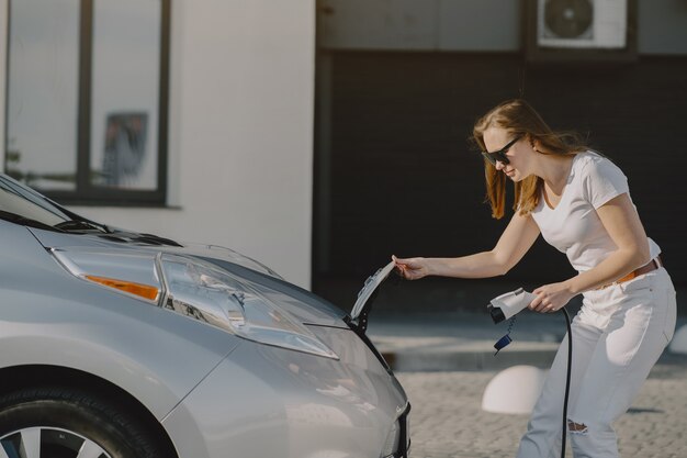 Carro elétrico de carregamento de mulher no posto de gasolina elétrico