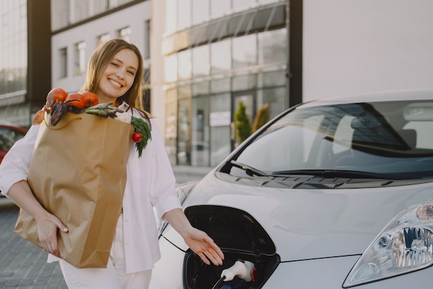 Carro elétrico de carregamento de mulher no posto de gasolina elétrico