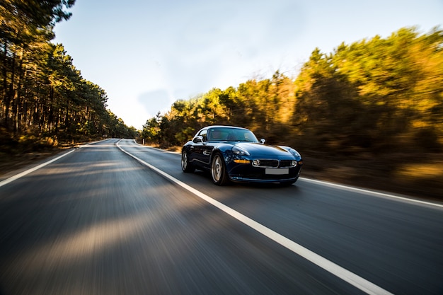 Foto grátis carro esporte de luxo preto dirigindo pela floresta.