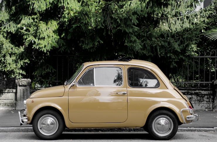 Foto grátis carro vintage na rua cercado por árvores sob a luz do sol