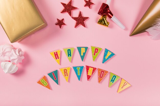 Carta de feliz aniversário com itens de festa e zéfiros em fundo rosa