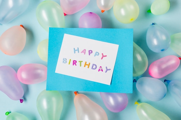 Cartão de feliz aniversário em balões contra o pano de fundo azul