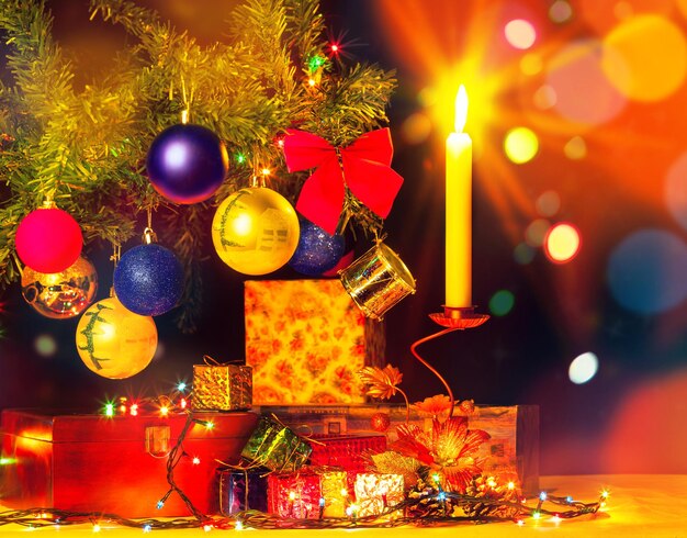 Cartão de férias de árvore de natal e enfeites. Feliz feriado. Objetos brilhantes. Caixas de presente e luz de velas com guirlandas