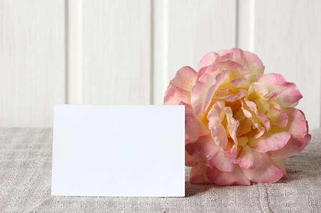 Cartão de visita vazio e uma maquete de rosa na mesa com um fundo de cartão de papel para o seu texto
