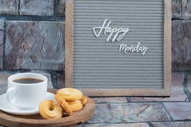 Foto grátis cartaz de feliz segunda-feira com um copo de bebida e biscoitos por perto