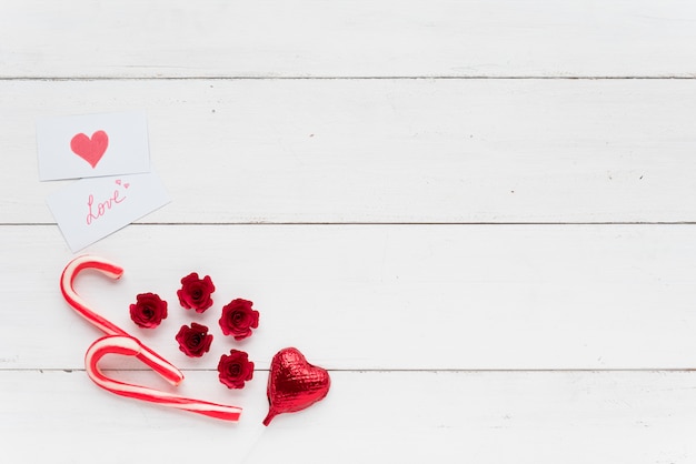 Cartões com inscrição de amor perto de coração decorativo e bastões de doces