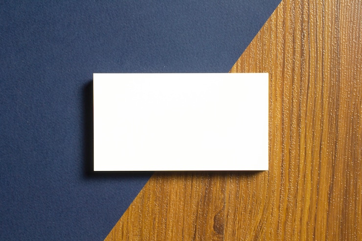 Foto grátis cartões de visita em branco metade de cada um deitar no papel texturizado azul e mesa de madeira