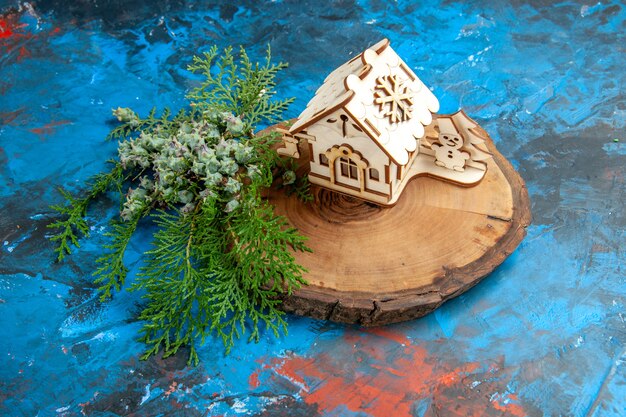 Casa de brinquedo de madeira de vista frontal com galhos de pinheiros na mesa azul