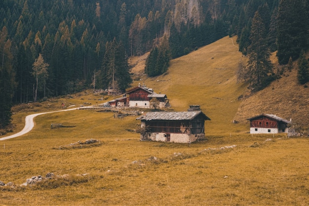 Casa marrom e branca em campo de grama verde perto da montanha marrom durante o dia