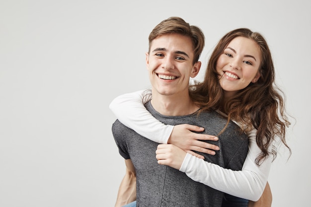 Casal abraçando e rindo perto da parede.