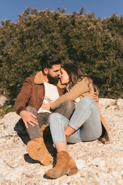 Foto grátis casal abraçando e sentado em uma pedra