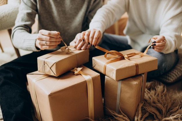 Casal abrindo presentes de Natal perto da árvore