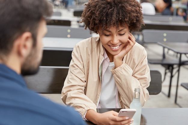 Casal adorável feliz posa em ambiente urbano em um café