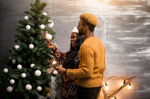 Casal afro-americano pendurado brinquedos em uma árvore de Natal