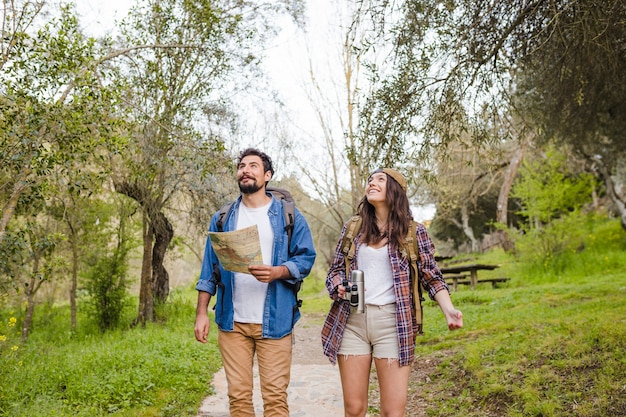 Casal alegre com mapa viajando na floresta