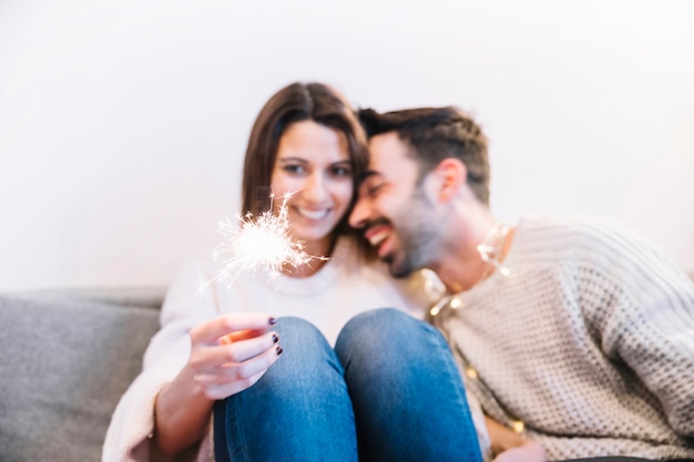 Casal alegre com sparkler no sofá