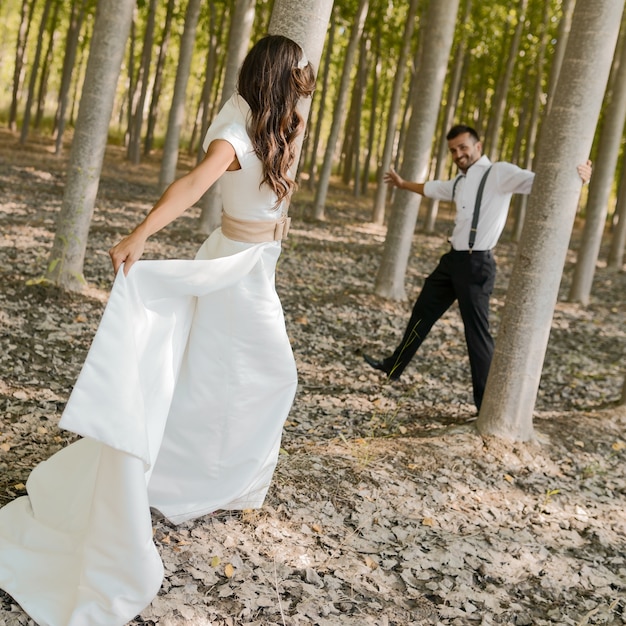 Foto grátis casal alegre que joga entre as árvores