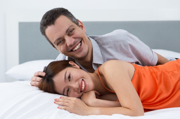 Casal alegre relaxando na cama confortável