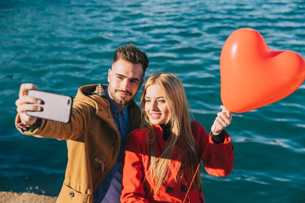 Casal alegre tomando selfie com balão