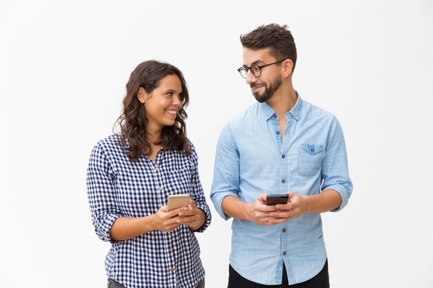 Casal alegre usando telefones celulares