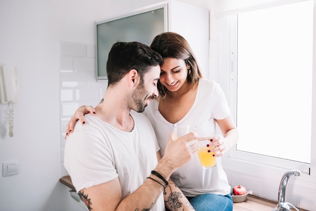 Casal amando desfrutando suco na cozinha