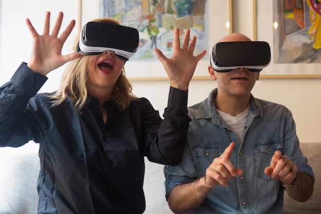 Casal animado usando fone de ouvido VR, gritando