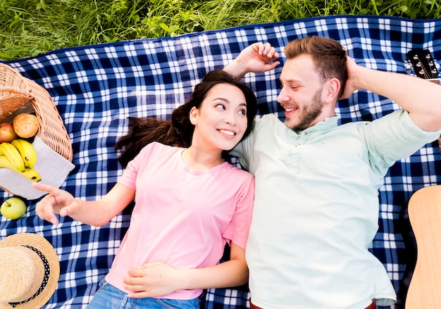 Casal apaixonado, deitado no pano de piquenique