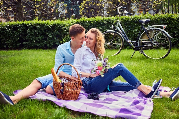 Casal apaixonado em um piquenique após passeio de bicicleta em um parque.