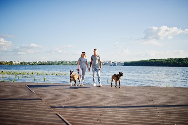 Casal apaixonado por dois cães pit bull terrier contra o lado da praia