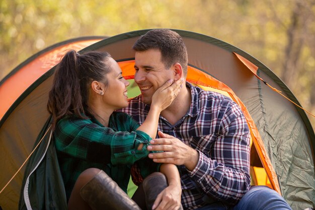 Casal apaixonado, sorrindo, olhando um para o outro na frente da tenda. Atmosfera romântica