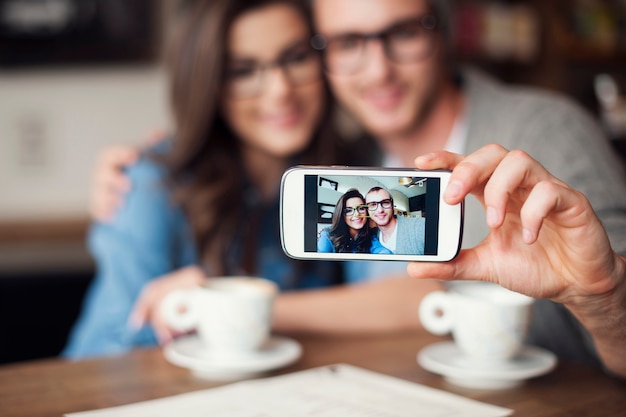 Casal apaixonado tirando uma selfie em um café