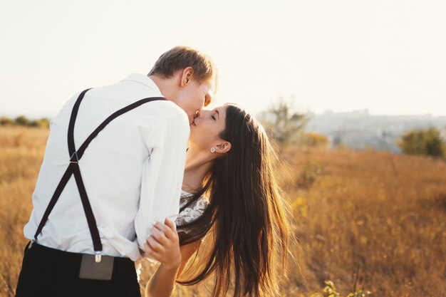 Casal apaixonado, vestido de branco beijando ao ar livre, tocando, gentl