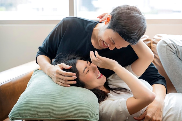 Casal asiático Casal apaixonado compartilhando emoções genuínas e felicidade abraçando na luz da manhã do sofá do sofá na sala de estar casa fundo interior conceito de isolamento em casa