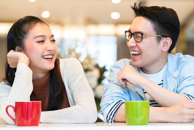 Casal asiático de felicidade ri sorrindo junto com humor de despensa de cozinha emocional casual relaxa com fundo interior do quarto