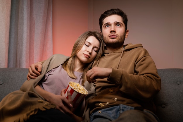 Casal assistindo tv e comendo pipoca