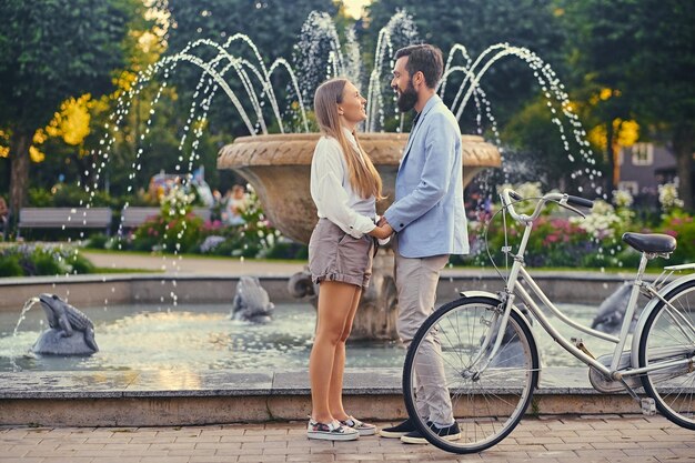 Casal atraente em um encontro está se beijando sobre fundo de fonte.