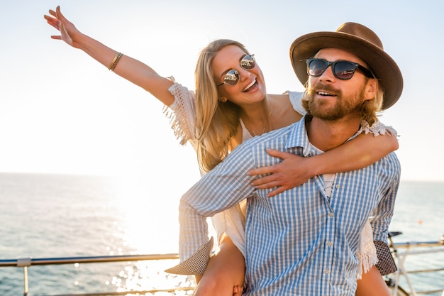 Casal atraente feliz rindo viajando no verão pelo mar, homem e mulher usando óculos escuros