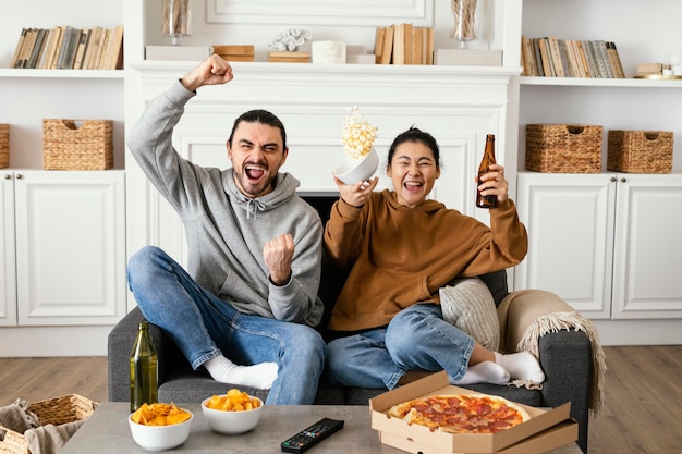 Casal bebendo cerveja e comendo salgadinhos