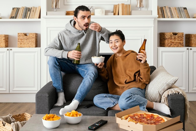 Casal bebendo cerveja e comendo salgadinhos