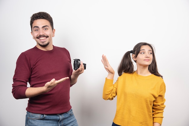 Casal bonito com câmera posando sobre uma parede branca.