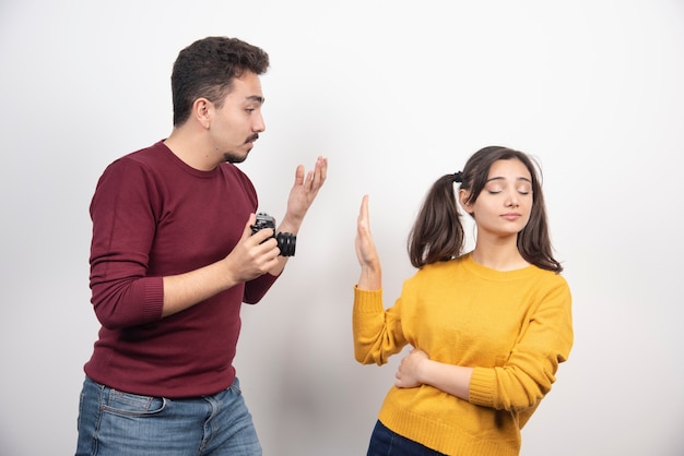 Foto grátis casal bonito com câmera posando sobre uma parede branca.