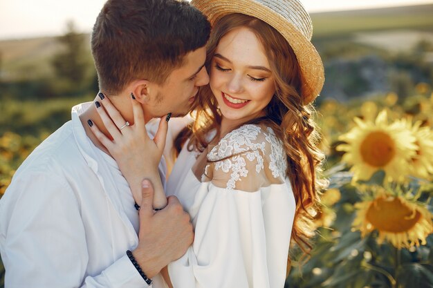 Casal bonito e elegante em um campo com girassóis