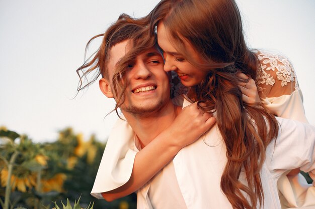 Casal bonito e elegante em um campo com girassóis