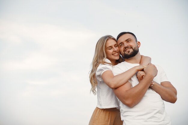 Casal bonito em um campo. Senhora em uma blusa branca. Cara em uma camisa branca