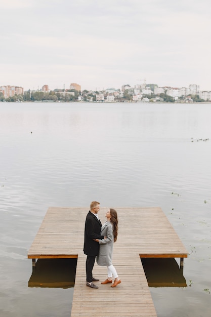 Casal bonito em um parque. senhora com um casaco cinza. pessoas no cais.